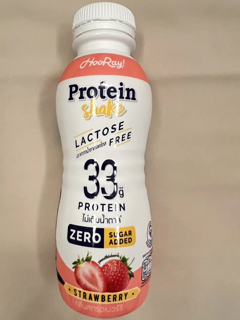 Front of a white and orange Hooray strawberry protein-shake bottle declaring 33 grams of protein and zero sugar added