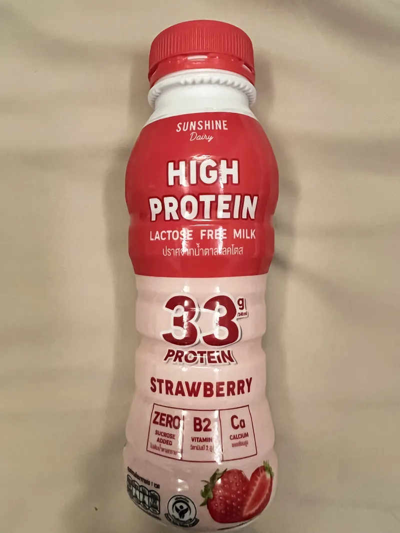 Front of a red and white Sunshine Dairy strawberry milk bottle declaring 33 grams of protein