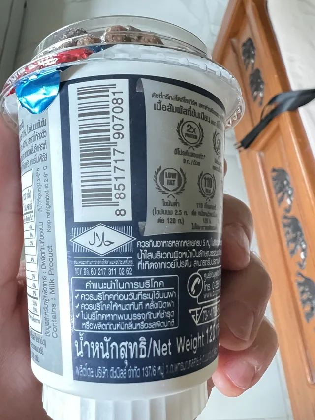 Side of the photographed Dutchie Greek Style 2X Protein cup showing barcode 8851717907081, 120 gram net weight, storage instructions, and package claims